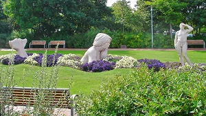 Skulpturen von Meerjungfrau und Mann im blühenden Kurpark