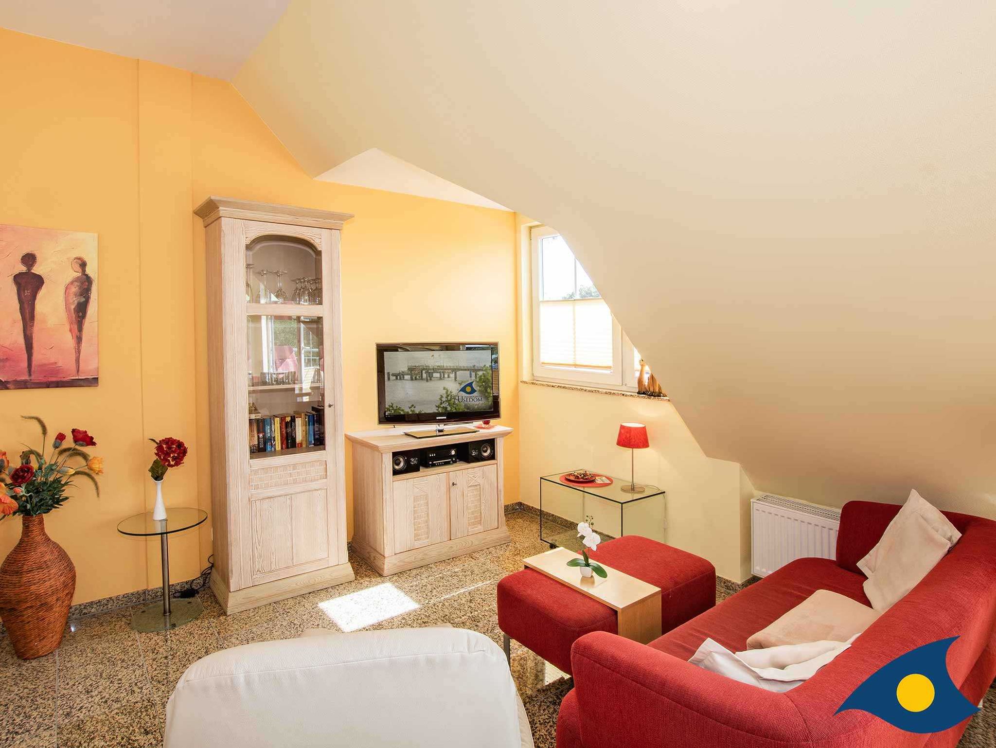 Das helle Wohnzimmer mit gemütlicher Couchgarnitur und Flachbild-TV