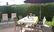 Terrasse vor dem Haus mit Sonnenschirm, Liegestühlen und Sitzgruppe
