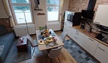 Wohnbereich mit offener Küche, Kamin und höhenverstellbarem TV